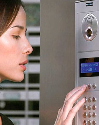 Mujer utilizando pantalla interior de videoportero en departamento de Providencia
